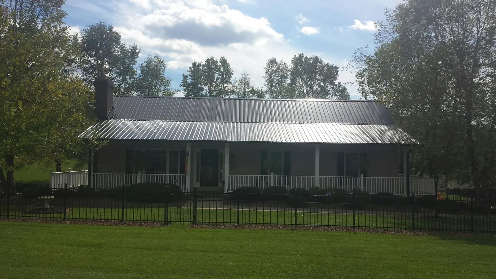 Gray metal roof on a brick ranch with a full width front porch — Gutter Guard Installation work by our crew in Albion